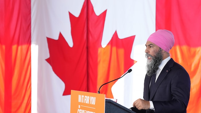 Jagmeet Singh derrière un lutrin et devant un drapeau canadien.