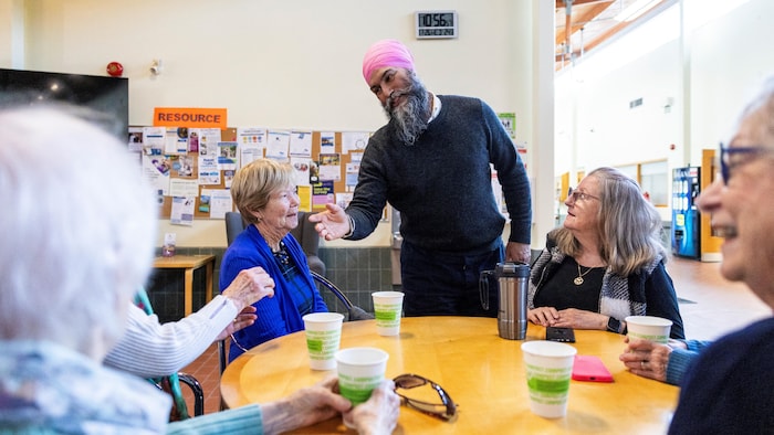 M. Singh salue des personnes âgées assises à une table.