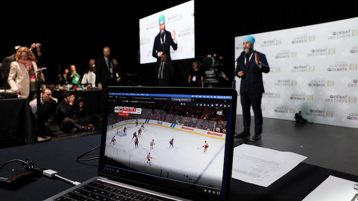 Une personne écoute le hockey sur son ordinateur pendant le point de presse de Jagmeet Singh.