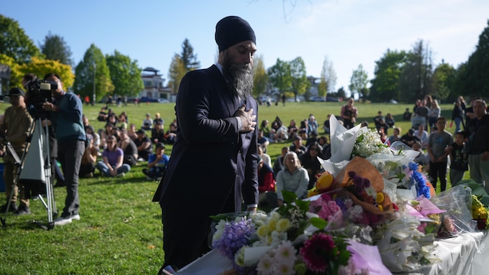 Jagmeet Singh se recueille devant une table où sont déposées des fleurs.