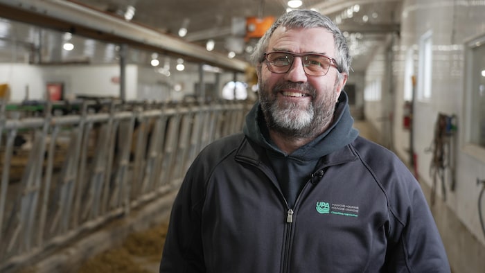 Un homme tout sourire dans une étable.