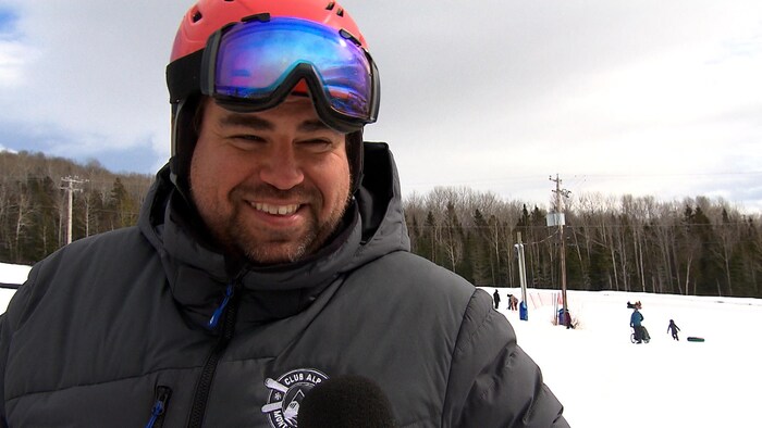 Jeames Keays, un homme souriant en tenue de ski regarde l'objectif.
