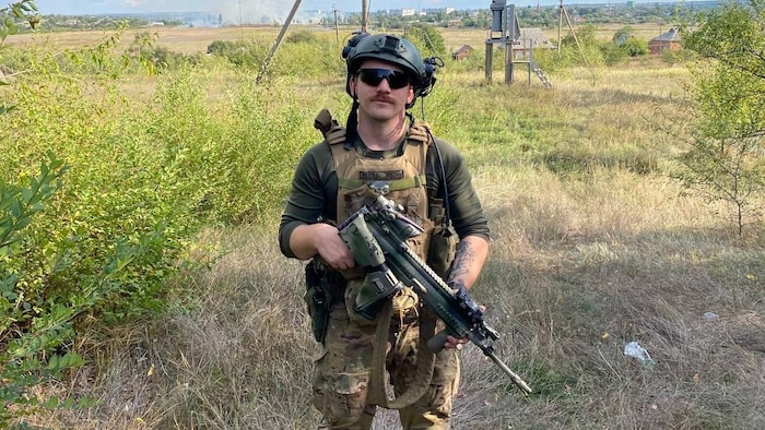 Un soldat dans un champ tient une arme.