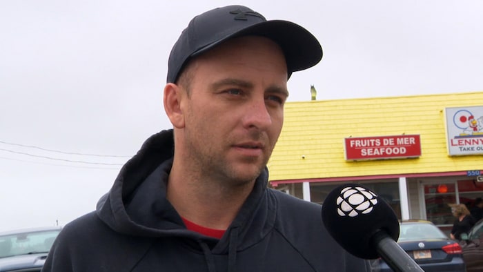 Un homme interviewé devant un restaurant.