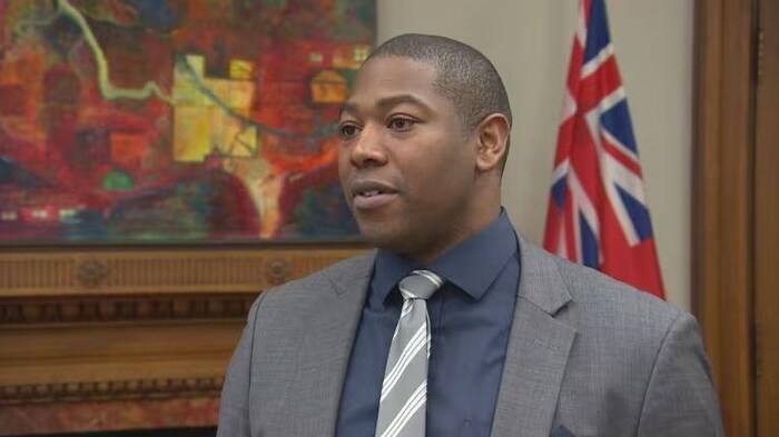 Jamie Moses devant un drapeau du Manitoba.