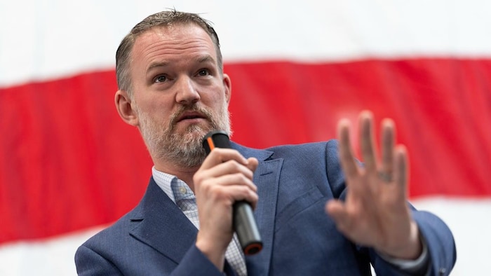 Un homme, micro à la main, prononce un discours.