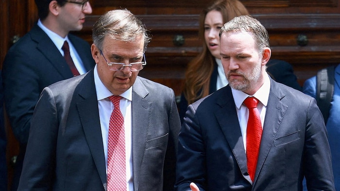 Les deux hommes en complet discutent à la sortie du palais.