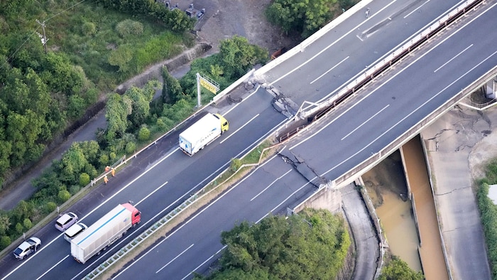 Une autoroute est comme plissée par le tremblement de terre. Des véhicules sont immobilisés devant le pli, qui crée une bosse boquant la circulation.