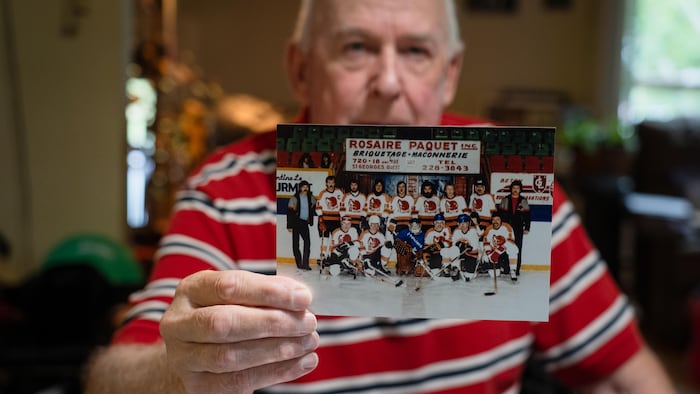 Un homme montre une photo d'une équipe de hockey.