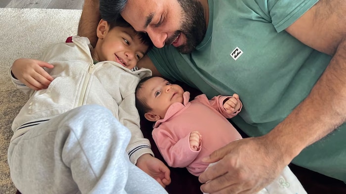 Jaskirat Singh Sidhu et ses enfants, un garçcon âgé de 3 ans et une fille de 3 mois, couché sur le sol.