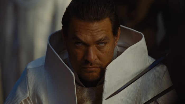 Un personnage du film au regard menaçant, dans une combinaison angulaire. 