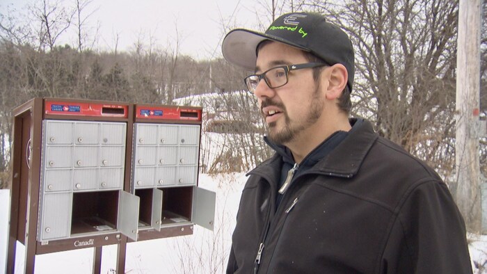 Jason Mougeot devant une boîte postale communautaire vandalisée de Postes Canada.