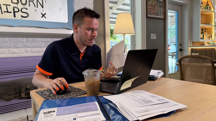 Un homme assis à une table devant son ordinateur avec des documents.