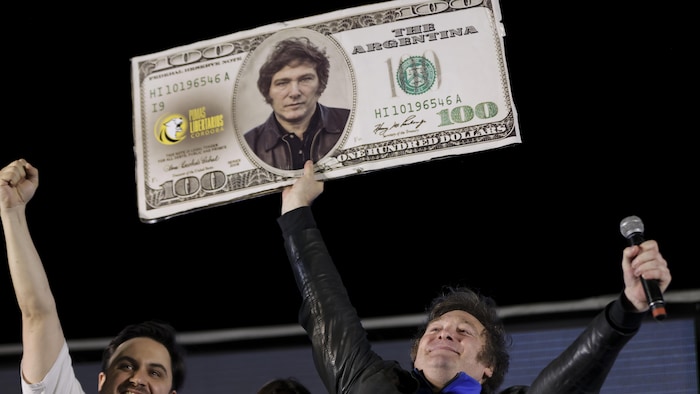Javier Milei brandit une pancarte montrant son visage sur un billet de 100 $ US.