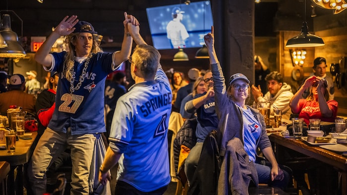 Des partisans des Blue Jays au bar Loose Moose célèbrent après un bon jeu lors du match 6 de la Série mondiale.