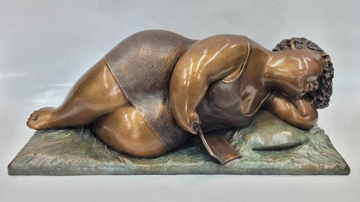 La sculpture d'une des fameuses femmes rondes de Rose-Aimée Bélanger. Cette fois, elle est couchée sur un lit et se détend après la lecture d’un livre.