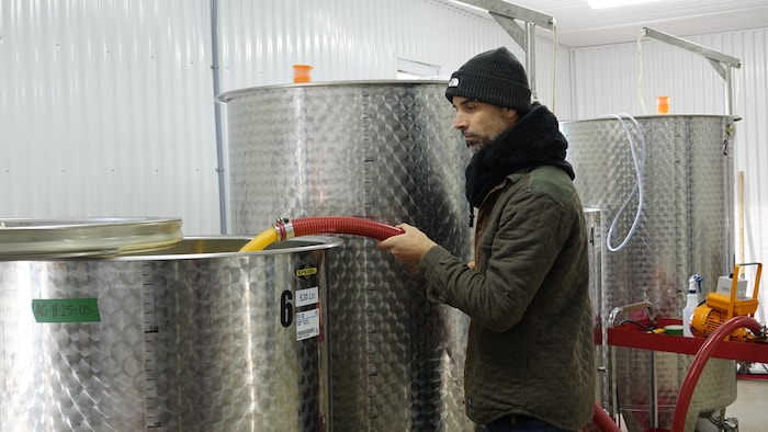 Jean-Charles Fleurent manipule un tuyau dans sa cuve de fermentation.