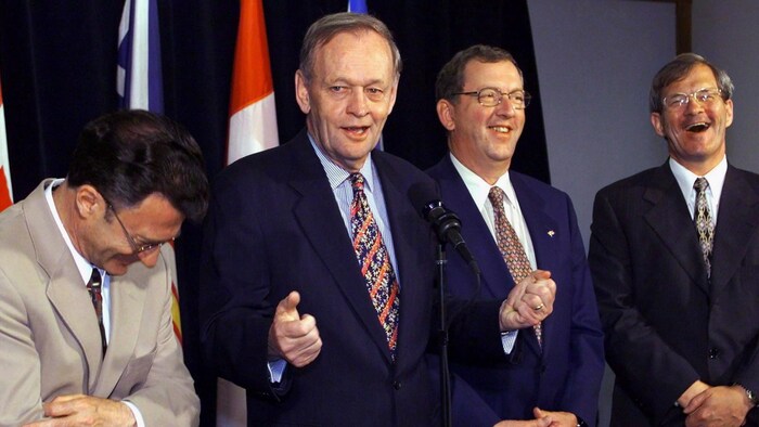 Flanqué de trois hommes qui éclatent de rire, Jean Chrétien semble fier de sa blague.