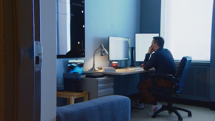 Une personne assise à un bureau regarde un moniteur.