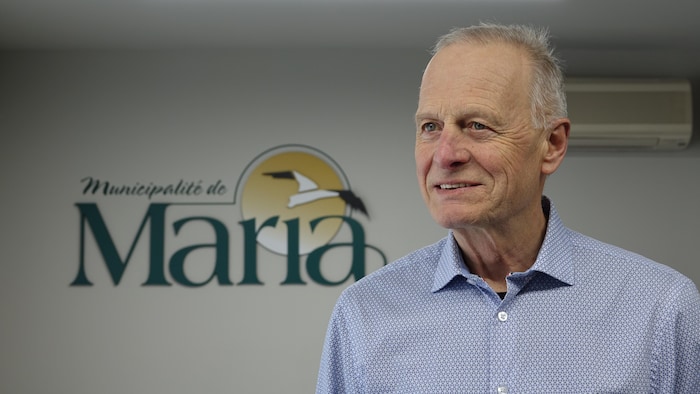 Le maire de Maria, Jean-Claude Landry, devant le signe de la Municipalité.