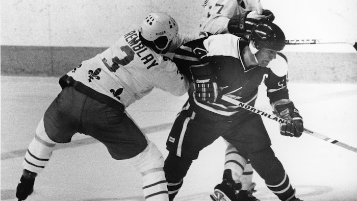 Deux joueurs des Nordiques sont en pleine empoignade pour empêcher un attaquant de l'équipe adverse de compter.