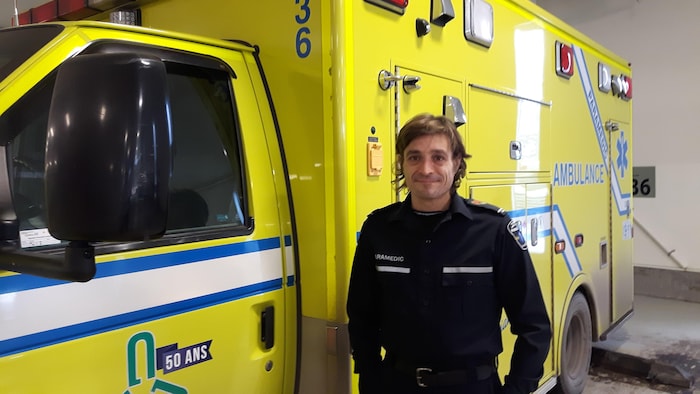 Jean-François Gagné prend la pose à côté d’une ambulance stationnée dans un garage.