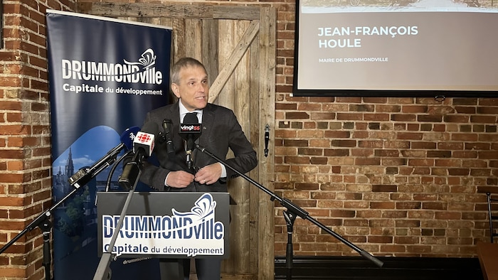 Jean-François Houle lors d'une conférence de presse. Plusieurs micros de médias sont devant son lutrin.