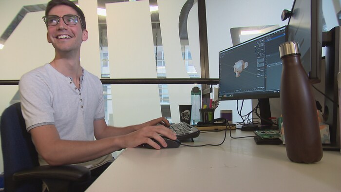 Jeune homme souriant devant un écran d'ordinateur