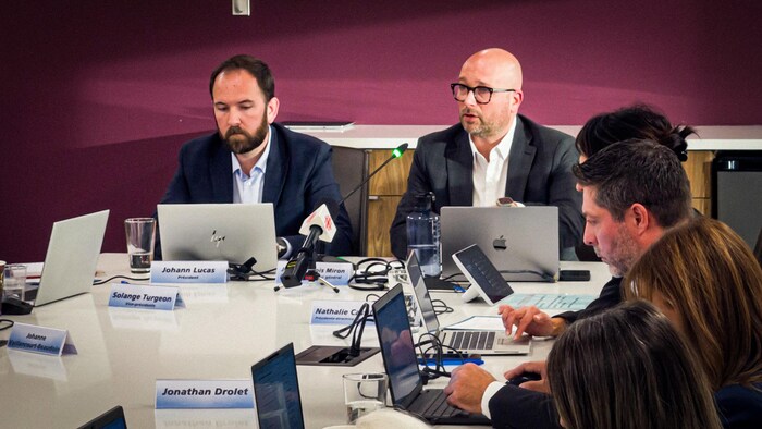 Jean-François Miron et Johann Lucas sont assis côte-à-côte au bout d'une table de conférence.