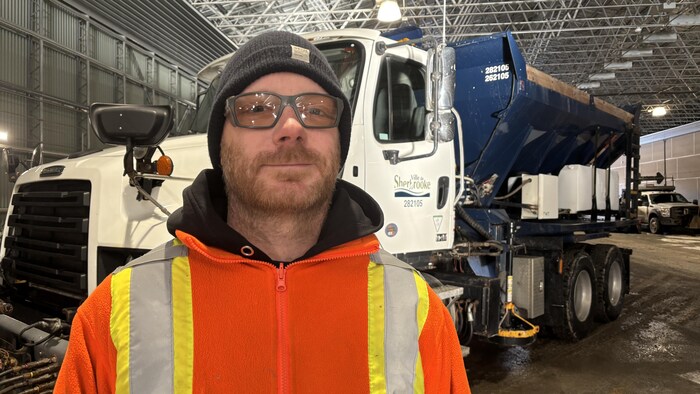 Jean-François Picard a un sourire en coin devant un camion de déneigement de la Ville de Sherbrooke. 