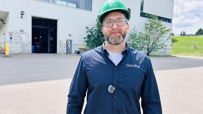 Un homme portant un casque devant une usine.