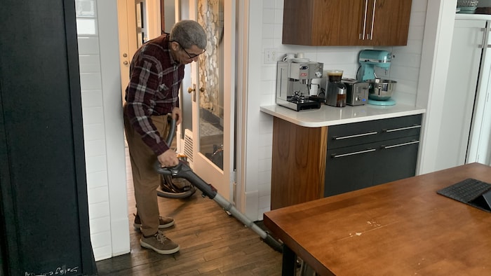 Jean Garant passe la balayeuse dans sa cuisine.