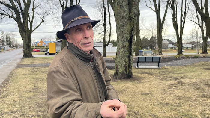 Jean Guilbert dans un parc avec un manteau brun. 