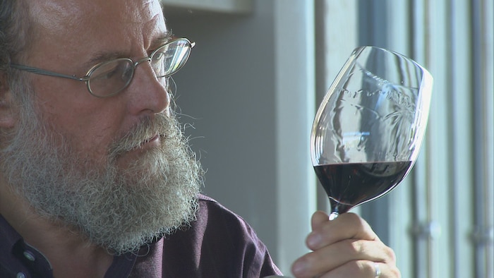 Jean-Laurent Groux tient un verre de vin rouge.