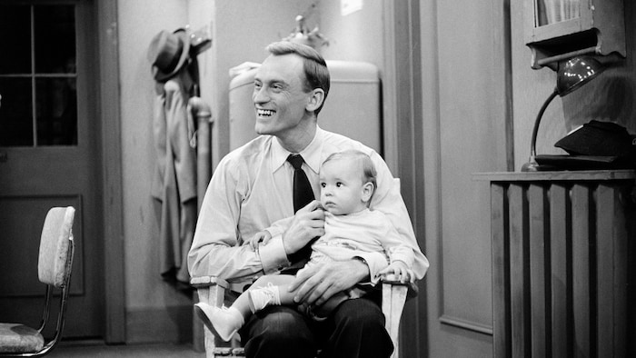 Jean-Louis Roux avec un bébé sur les genoux. 