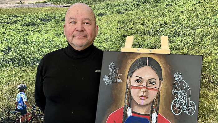 L'artiste Jean-Luc Hervieux pose à côté d'une de ses toiles.