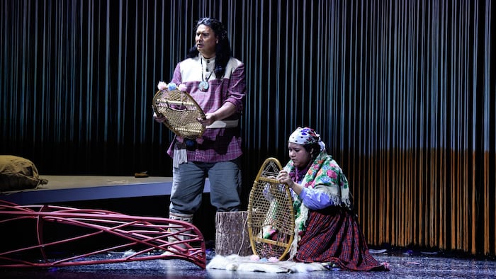 Deux acteurs en tenues traditionnelles innues sur scène. 