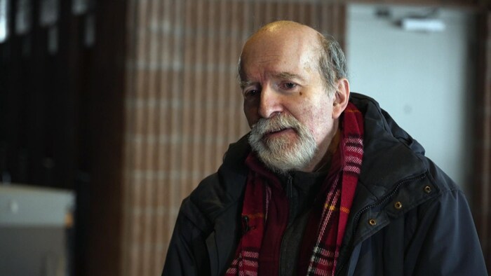 Un homme parle à la caméra.