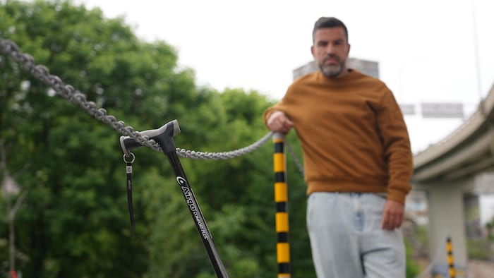 Un homme debout, juste derrière une canne accrochée à une chaîne.