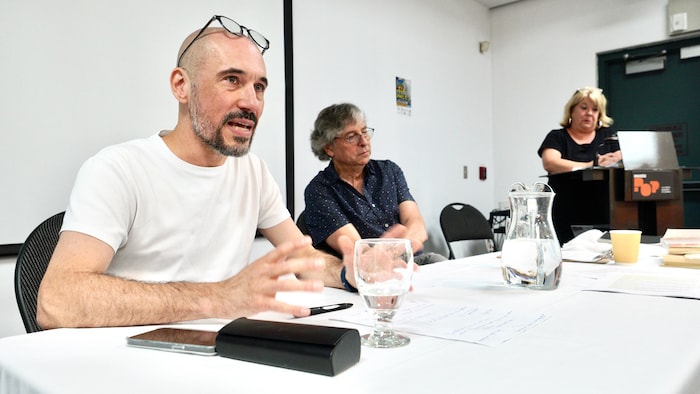 Jean-Philippe Pleau est assis à une table aux côtés d’un homme et d’une femme.