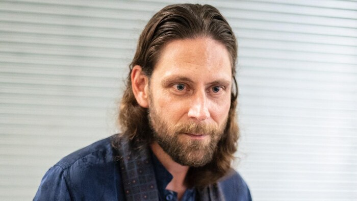 Un homme porte une chemise bleue. 