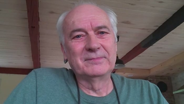 Un homme aux cheveux blancs regarde l'objectif.