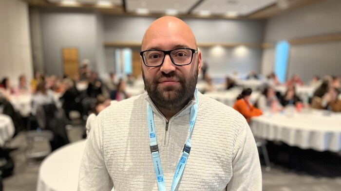 Jean-Sébastien Blais au Centre des congrès de Rouyn-Noranda. Une trentaine de personnes sont réunies à des tables près de lui.