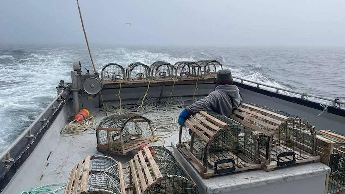 Un capitaine de dos sur le pont d'un bateau de pêche au homard.