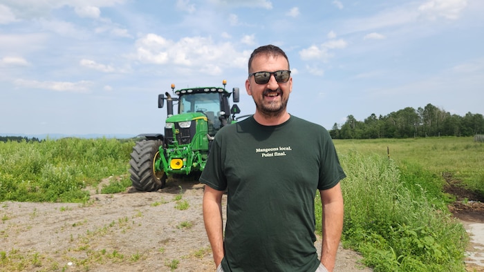 Portrait de Jean-Thomas Maltais souriant devant un tracteur.