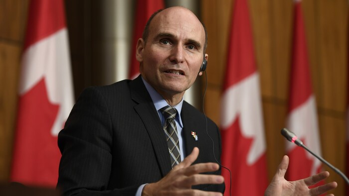 Jean-Yves Duclos assis durant une conférence de presse.