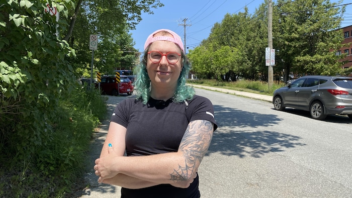 Jeane Benjamin sur le bord de la rue avec des voitures à l'arrière.
