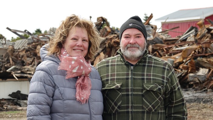Une photo de Jeanne Bourgeois et François Dumont, à l'extérieur, devant les ruines de leur entreprise.