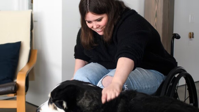 Carrière, shown petting a dog, does simple daily exercises with her hands and goes to rehabilitation therapy twice a month to work with specialists. She says one of the most important changes in recent months is that she has been able to return to work as a screenwriter. (Esteban Cuevas/CBC)