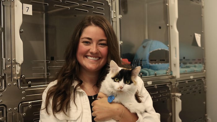 Jeanne Mercier sourit en tenant un chat rescapé.